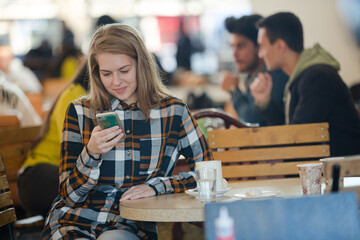 Smiling young woman using smart phone in cafe