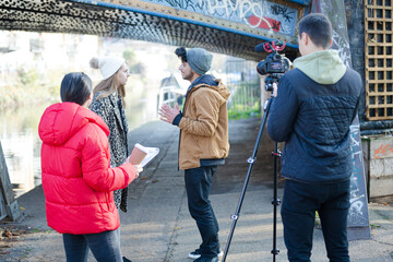 Young adults vlogging under urban bridge