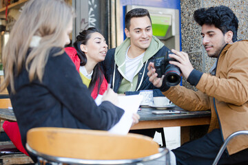 Young adult college students with digital camera at sidewalk cafe
