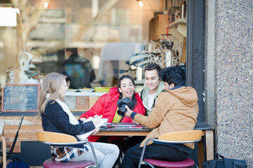 Young adult college students with digital camera at sidewalk cafe