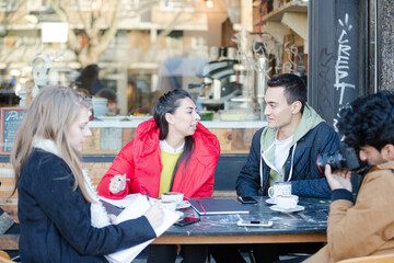 Young adult friends talking at sidewalk cafe