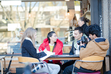 Fototapeta na wymiar Young adult friends talking at sidewalk cafe