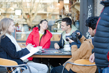 Young adult college students with digital camera at sidewalk cafe