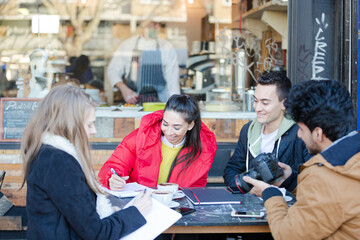 Young adult friends talking at sidewalk cafe