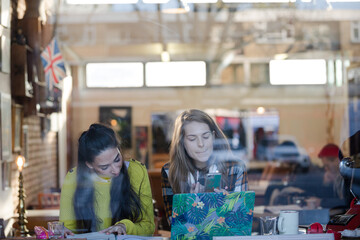 Young female college students studying at cafe window