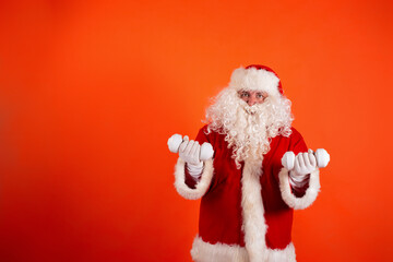 Cute toast santa claus with dumbbells in his hands on an orange background. Sports nutrition and exercise for weight loss.