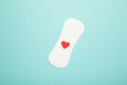 Menstrual pads on blue background. Menstruation cycle. Hygiene and protection. A heart on a menstrual pad.