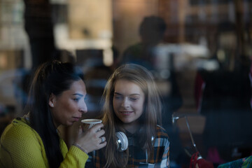 Young female college students studying at laptop in cafe window