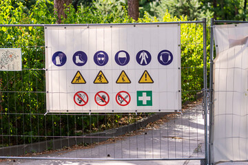 Information panel with forbidden and permissible signs at the construction site metal fence, closeup