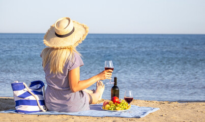 Fototapeta na wymiar Beautiful smiling woman with a glass of wine on the beach. Fruit red wine.