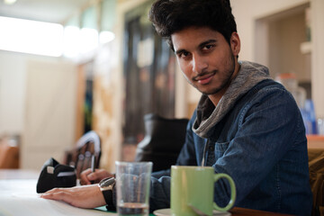 Portrait confident young male college student studying in cafe