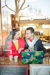 Young couple using smart phone and laptop in cafe