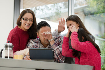 Happy family using digital tablet at kitchen table