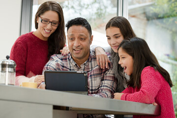 Happy family using digital tablet at kitchen table