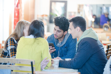 Young adult friends using smart phones at cafe table