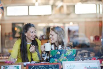 Young female college students studying at laptop in cafe window