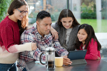 Happy family using digital tablet at kitchen table