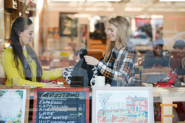 Smiling female college students studying at cafe window
