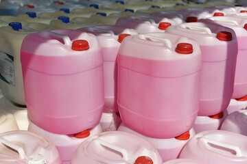stacked plastic jerrycans with pink liquid - obrazy, fototapety, plakaty