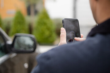 Personal perspective man setting car alarm from smart phone