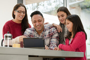 Happy family using digital tablet at kitchen table