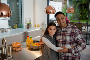 Portrait happy father and daughter hugging in kitchen