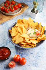 A blue bowl with cheese tortilla chips and a chilli cheese dip on a blue marble surface