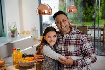 Portrait happy father and daughter hugging in kitchen