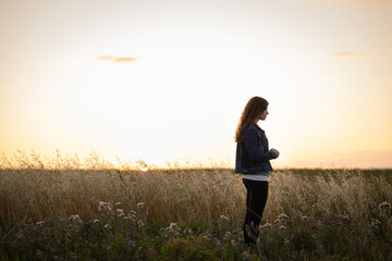 young woman standing in field praying, with copy space