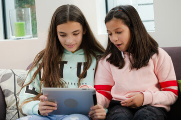 Sisters using digital tablet on living room