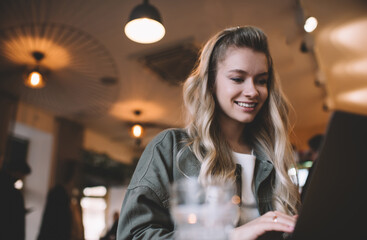 Positive lady working on laptop in cafe