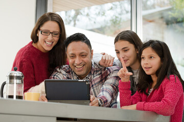 Happy family using digital tablet at kitchen table