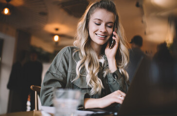 Lady speaking on phone and working on laptop in cafeteria