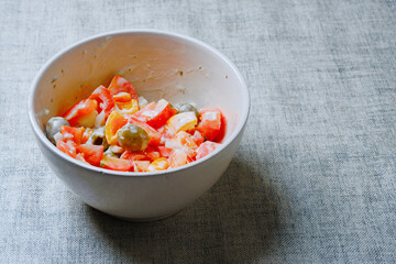 Simple home made salad with fresh tomato, olives and pepper and sour cream in a small bowl. Vegetarian food concept.