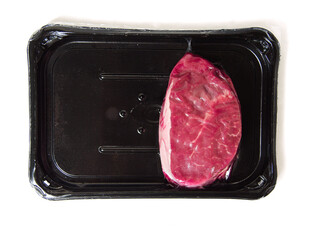One fresh raw piece of fillet steak on a black plastic tray and a red heart. Love meat theme. Butcher product. High quality beef cut. White isolated background. Meat industry