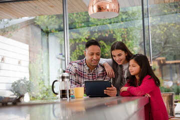 Happy family planning vacation at digital tablet in kitchen