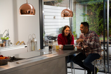Couple financial planning at digital tablet in kitchen