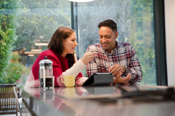 Couple financial planning at digital tablet in kitchen