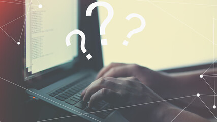 Closeup of a person solving a problem on the laptop with illustrative question marks on it