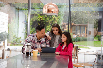 Happy family using digital tablet at kitchen table