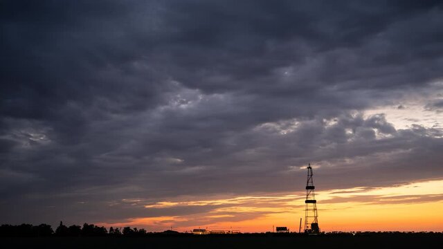 Timelapse of the life of a rig used to explore the gas field, against the background of moving evening clouds, at sunset.