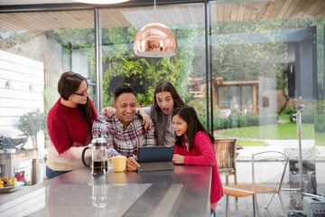 Happy family using digital tablet at kitchen table