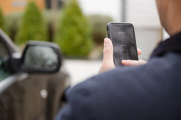 Personal perspective man setting car alarm from smart phone