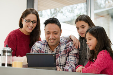 Happy family using digital tablet at kitchen table