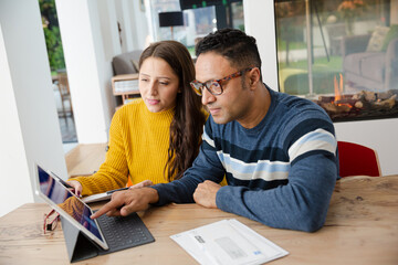 Couple paying bills online, using fingerprint log on at digital tablet