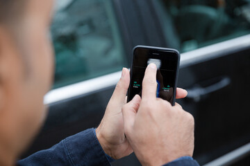 Man setting car alarm from smart phone in driveway