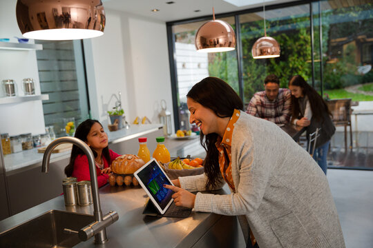 Mother and daughter talking, using digital tablet in kitchen - Powered by Adobe