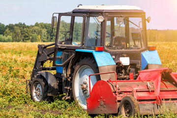 Modern wheeled agricultural tractor with harvesting equipment on an field