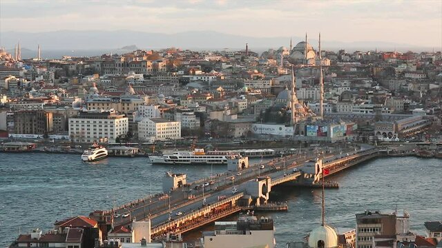 View of the Galata bridge and mosques at sunset. A lot of seagulls are flying, tourist boats are floating