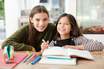 Girl helping young sister with homework